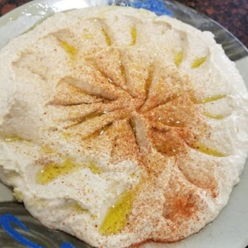 Creamy hummus with a swirl design, drizzled with olive oil and sprinkled with paprika.