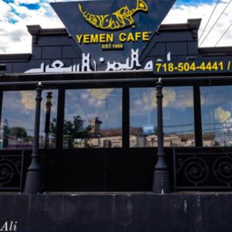 Exterior of Yemen Cafe & Restaurant with its black facade, yellow sign, and large windows.
