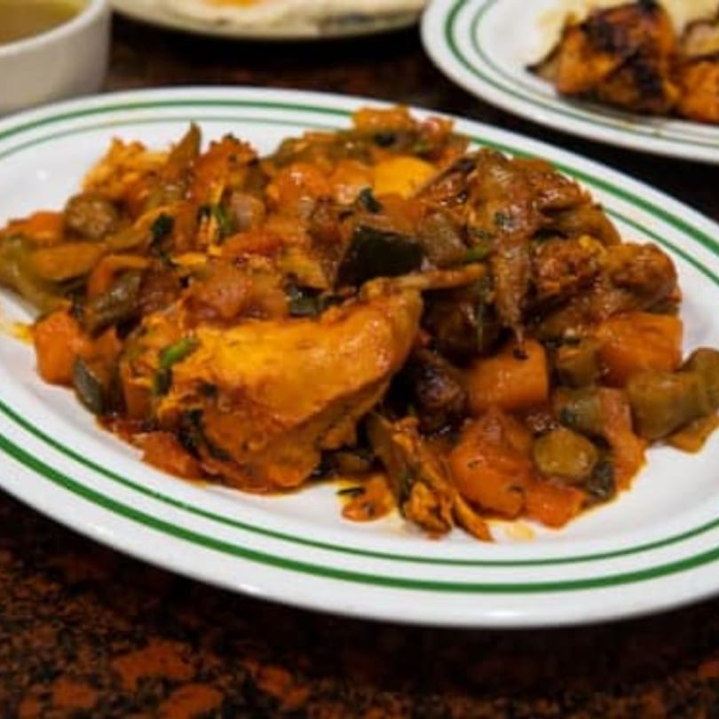 A plate of Yemen Cafe's chicken and vegetable stew, featuring chicken, eggplant, and potatoes in a rich sauce.