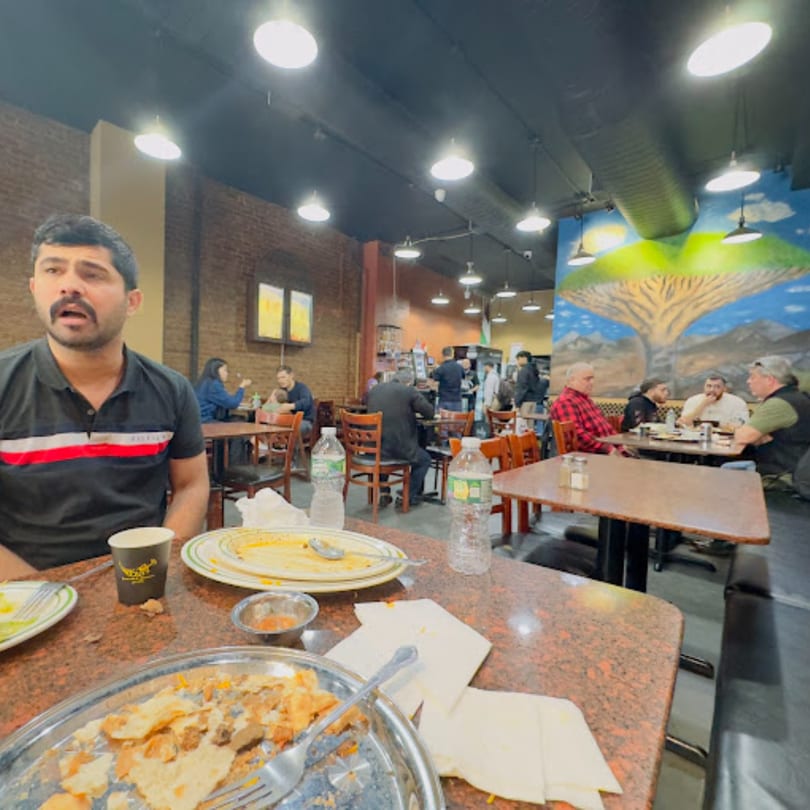 Diners enjoying Middle Eastern food at Yemen Cafe & Restaurant, with a man in the foreground.
