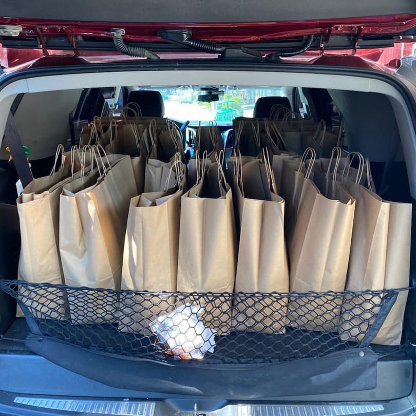 Numerous brown paper bags, likely filled with takeout orders from Yemen Cafe, packed in a car's trunk.