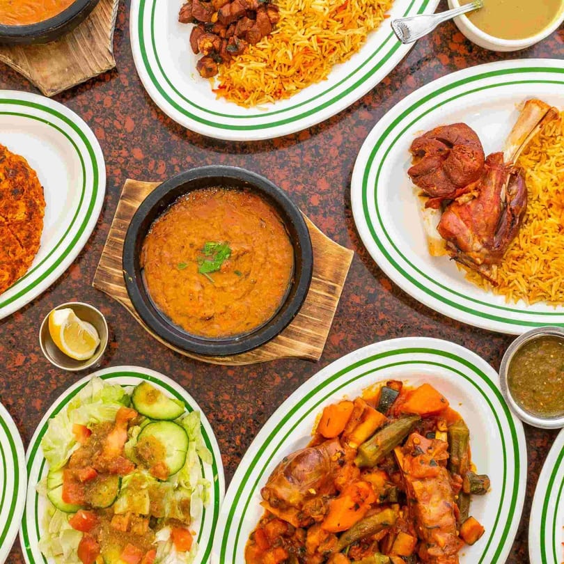 A top-down view of a table laden with various Yemeni dishes, including rice, meat, stews, and salad.